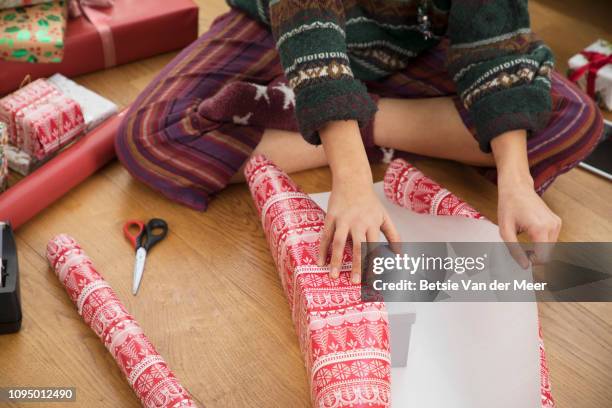 woman wraps christmas present at home. - avvolto foto e immagini stock