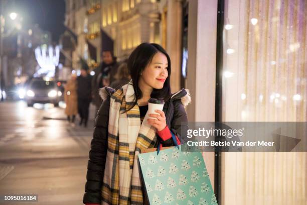 asian woman shopping, looking in shop window while walking. - europe asian culture stockfoto's en -beelden