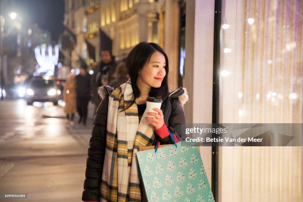 Asian woman shopping, looking in shop window while walking.