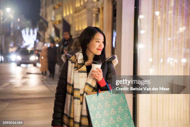 asian woman shopping, looking in shop window while walking. - window shopping stock pictures, royalty-free photos & images
