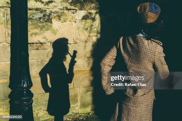 elegant lady smoking pipe projecting shadow of herself on wall - sherlock holmes stock pictures, royalty-free photos & images