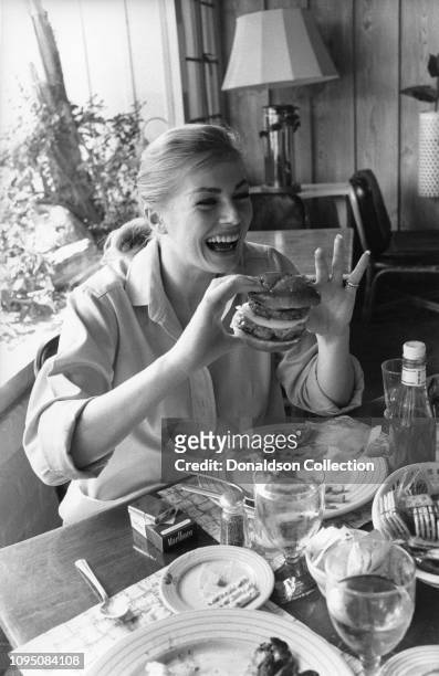 Swedish actress Anita Ekberg eating a hamburger poses for a photo on April 22, 1956 in Palm Springs, California.