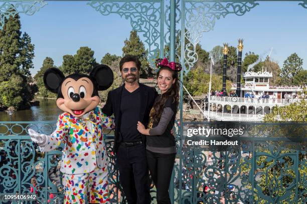 In this handout photo provided by Disneyland Resort, John Stamos and Caitlin McHugh Stamos celebrate their first wedding anniversary alongside Mickey...