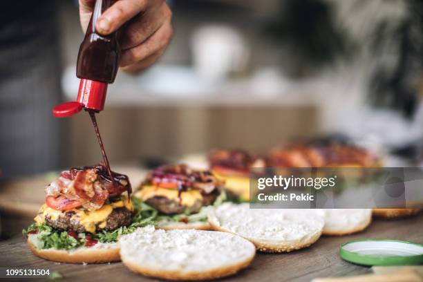 chef spicing hamburgers with juicy chilly sauce - pouring sauce stock pictures, royalty-free photos & images