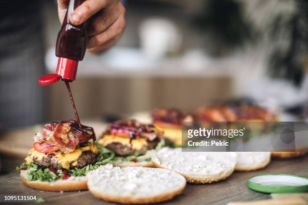 chef spicing hamburgers with juicy chilly sauce - burger on grill imagens e fotografias de stock