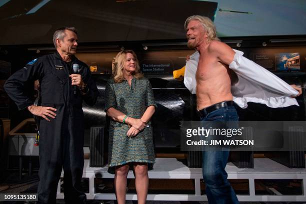Virgin Galactic founder Sir Richard Branson takes off his shirt to don a t-shirt that says "Future Astronaut Training Program" that was given to him...