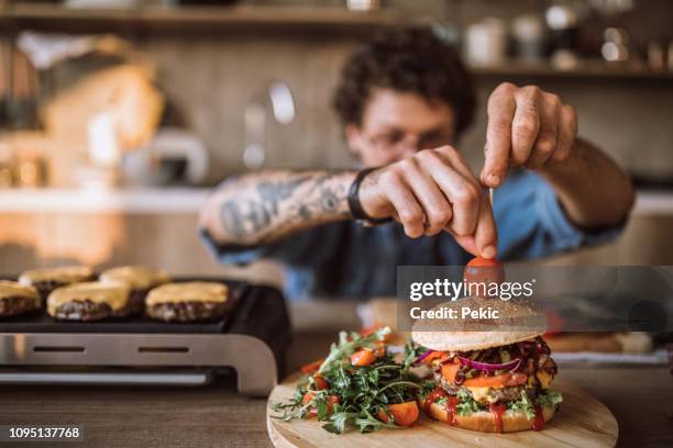 het versieren van lekkere hamburgers - burgers stockfoto's en -beelden