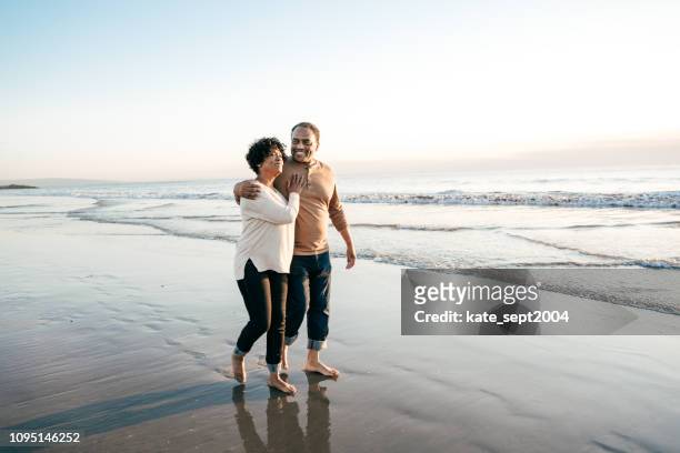 senior mannen lopen met senior vrouwen op het strand - beach walking stockfoto's en -beelden