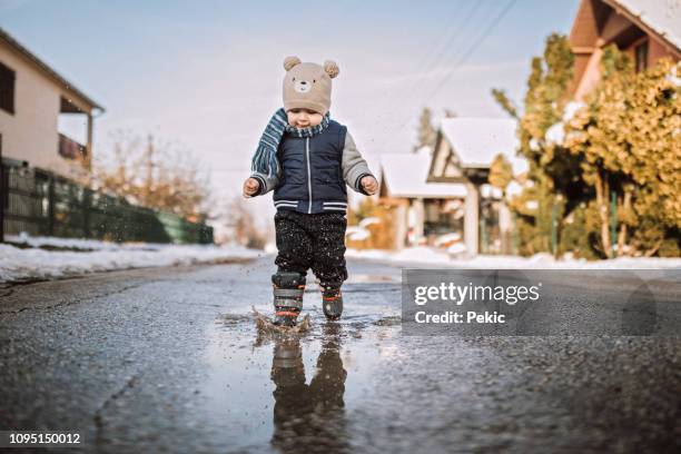 baby boy running happily through puddles - baby boot stock pictures, royalty-free photos & images