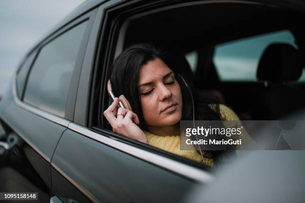 young woman on car with headphones - car listening to music imagens e fotografias de stock