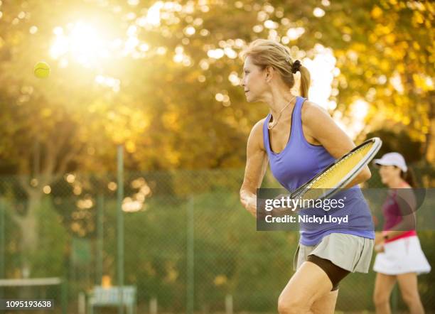 shot of mature women playing tennis. - tennis adult stock pictures, royalty-free photos & images