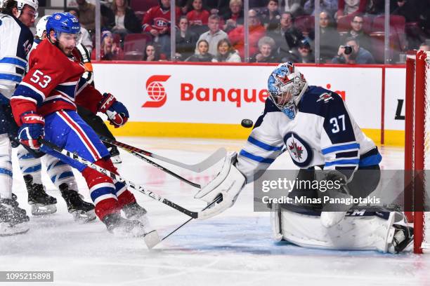 Goaltender Connor Hellebuyck of the Winnipeg Jets makes a save on Victor Mete of the Montreal Canadiens during the NHL game at the Bell Centre on...