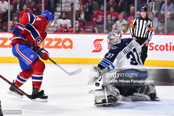 Goaltender Connor Hellebuyck of the Winnipeg Jets makes a glove save near Charles Hudon of the Montreal Canadiens during the NHL game at the Bell...