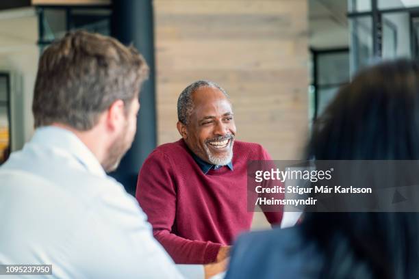 happy mature male manager sitting with colleagues - mature adult stock pictures, royalty-free photos & images