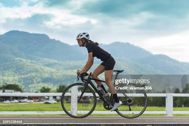 asian healthy cyclist girl wearing helmet cycling and exercise on bicycle in sprint track and open road - ciclista foto e immagini stock