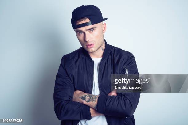 portrait of upset young man wearing bomber jacket - rapper stock pictures, royalty-free photos & images