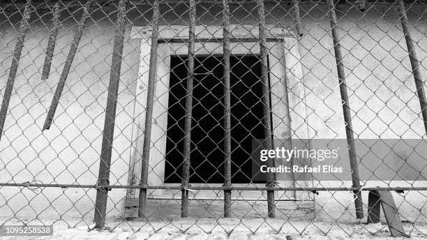 wooden window behind metal grate and iron bars - prison window stock pictures, royalty-free photos & images