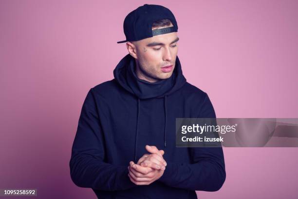 portrait of rebellious young man wearing hooded shirt - rapper stock pictures, royalty-free photos & images