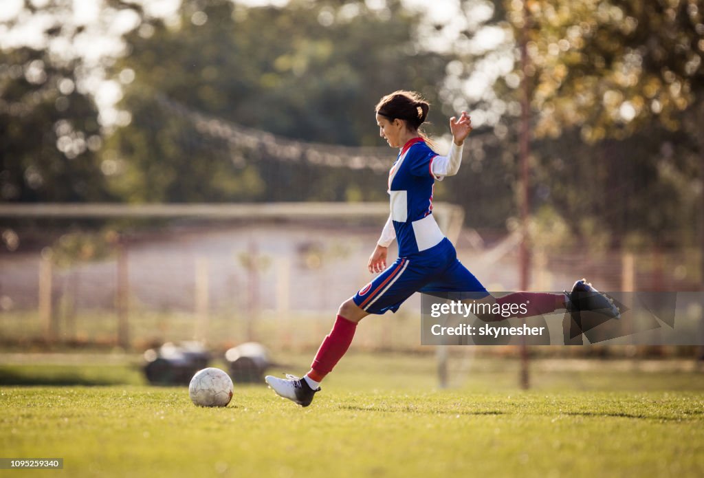 Teenage fotbollspelare på att sparka bollen under matchen.