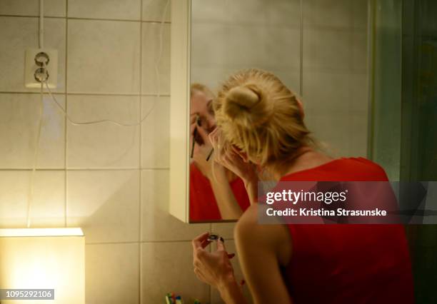 a woman applying make-up in front of a mirror - sumo knot stockfoto's en -beelden
