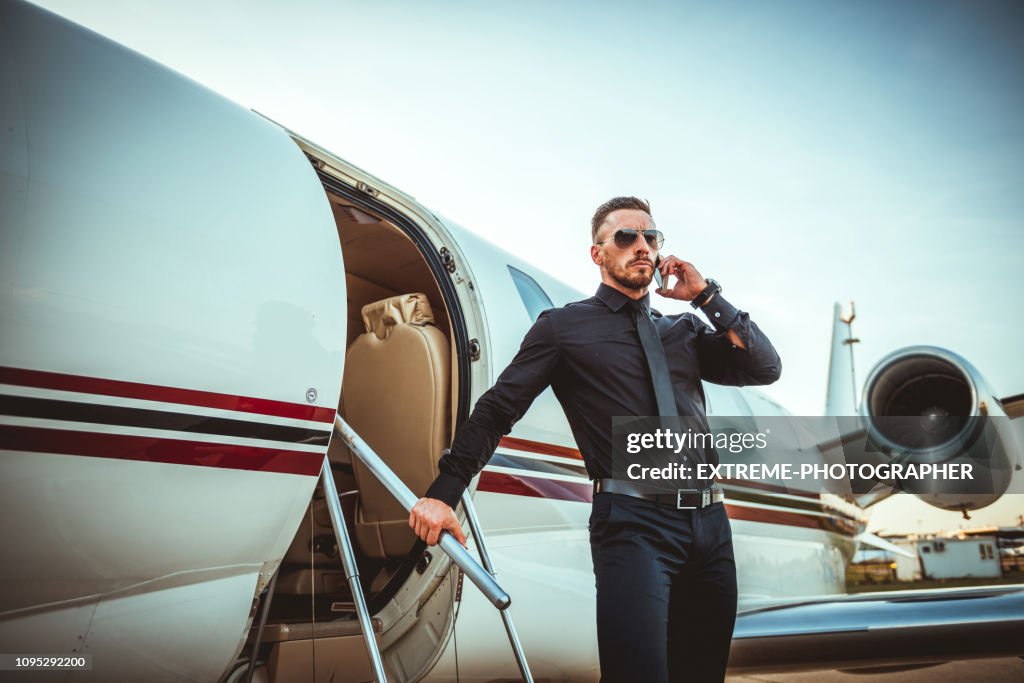 Heck reichen Jüngling Aussteigen aus einem privat-Jet während des Gesprächs auf dem Handy