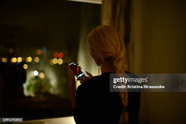 woman taking photo with her mobile phone through a window at night - ausblick stock-fotos und bilder