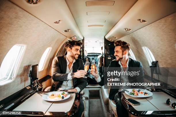 two managers putting their glasses together in a celebratory toast aboard a private airplane - first class champagne stock pictures, royalty-free photos & images