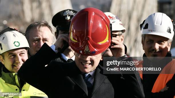 Italys Prime Minister Giuseppe Conte puts on a firefighter's helmet during a visit to the demolition site of the western section of the remains of...