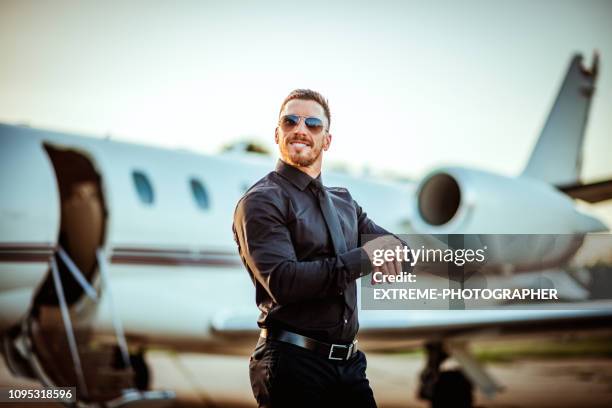 reiche und erfolgreiche jungunternehmer blick auf seine uhr vor einem privaten flugzeug - sunset society stock-fotos und bilder