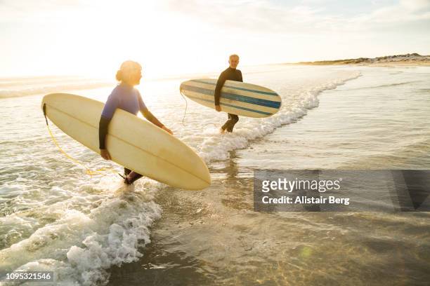 senior couple after a sunset surf together - ideal wife stock pictures, royalty-free photos & images