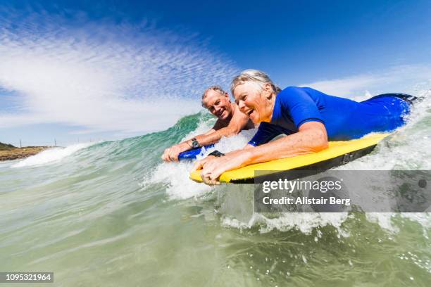 senior couple bodyboarding together - adrenalina fotografías e imágenes de stock