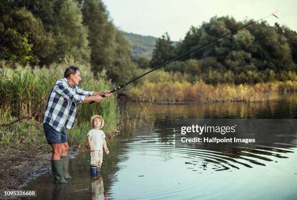 a senior man with a toddler boy fishing together on a lake. copy space. - freshwater fishing stock photos et images de collection