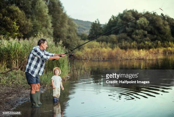 a senior man with a toddler boy fishing together on a lake. copy space. - freshwater fishing stock pictures, royalty-free photos & images