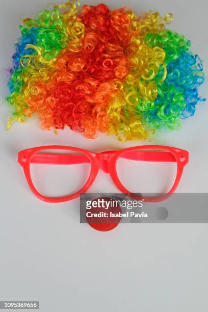 funny clown face formed with colorful wig, glasses and red nose on white background - joker stock pictures, royalty-free photos & images