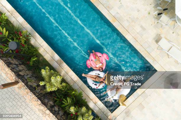 friends having fun with inflatable float at swimming pool - aerial view - swimming pool top view stock pictures, royalty-free photos & images