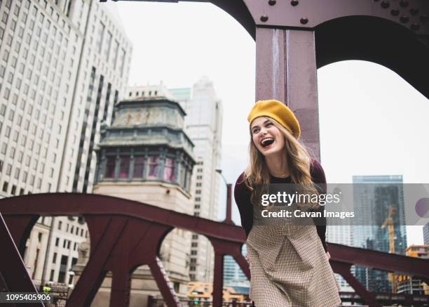 cheerful teenage girl standing on bridge against buildings in city - cook county illinois stock-fotos und bilder