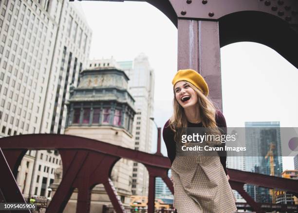 cheerful teenage girl standing on bridge against buildings in city - cook county illinois stock pictures, royalty-free photos & images