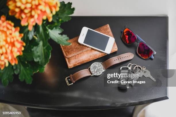 high angle view of chrysanthemums by personal accessories on table at home - car keys table stock-fotos und bilder