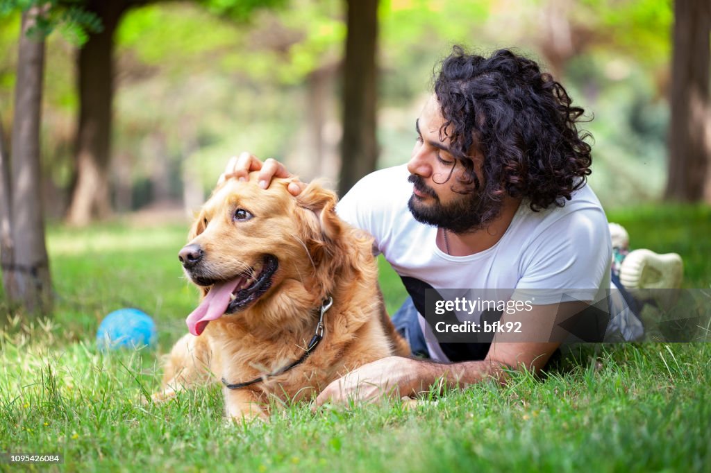 Young man spending time with his Golden Retriever outdoors.