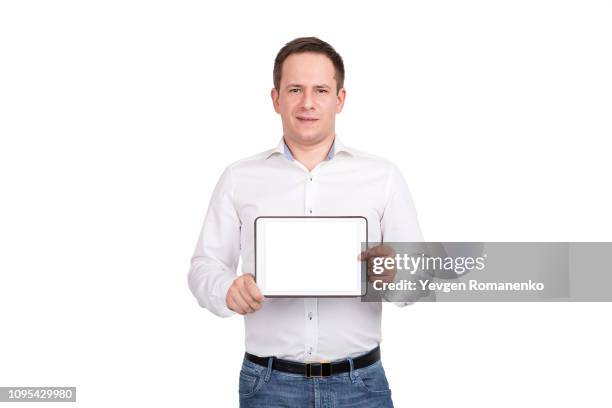 happy young man showing blank tablet computer screen over white background. looking at camera - white shirt template stock pictures, royalty-free photos & images