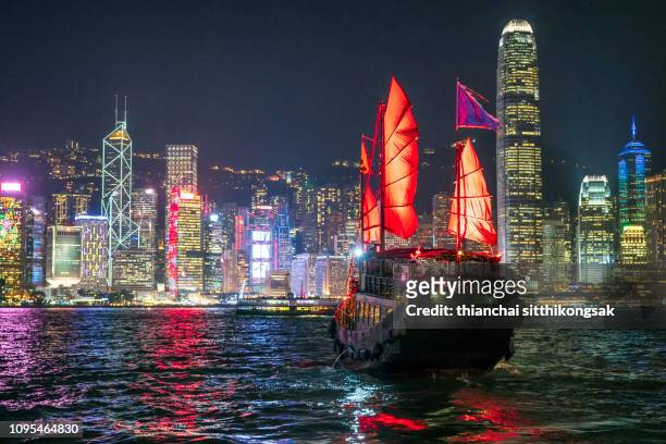 cityscape hong kong and traditional junkboat at night - hong kong junk boat stock pictures, royalty-free photos & images