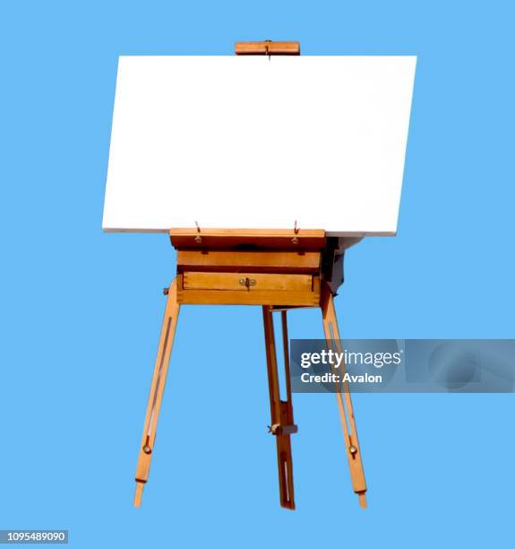 Blank canvas rests on a easel isolated on light blue background.