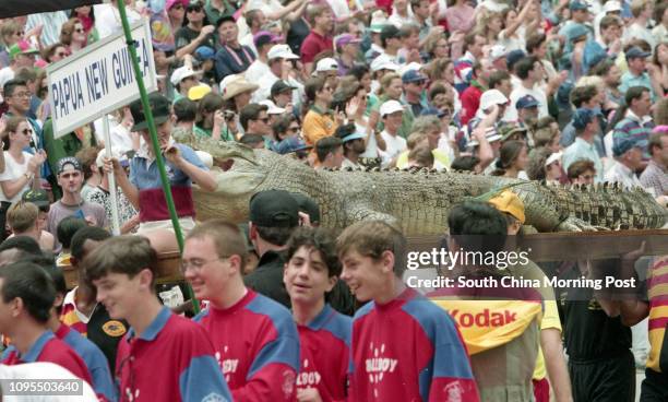 Members of the Papua New Guinea team march past the crowd with a real crocodile stuffed and flown in from Port Moresby at the Cathay Pacific /...