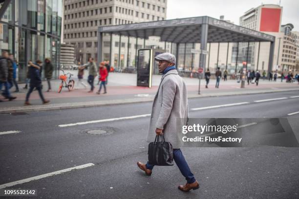 young businessman crossing the street coming back from work - pedestrian winter stock pictures, royalty-free photos & images