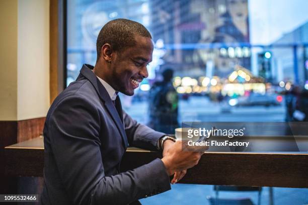 vue latérale d’un jeune homme en costume à l’aide de son smartphone dans un café - businessman in black suit photos et images de collection