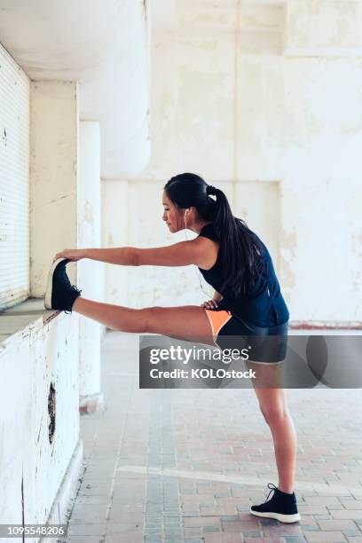 young woman stretching in urban location - tocar los dedos de los pies fotografías e imágenes de stock