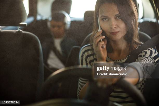 woman using mobile phone while driving a car - mom stuck in traffic imagens e fotografias de stock