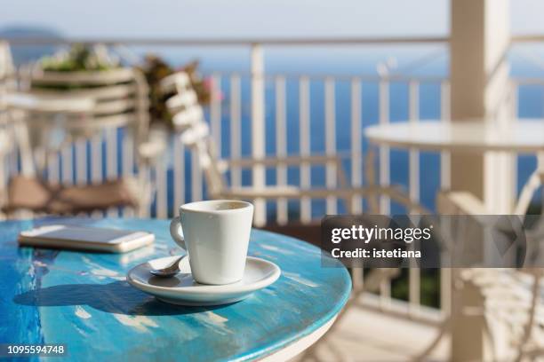 empty coffee cup and smart phone on blue table - enjoying coffee cafe morning light stock-fotos und bilder