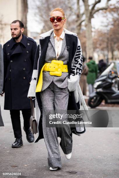 Elina Halimi, wearing a Celine long coat, grey suit, big yellow belt and grey Hermes bag, is seen in the streets of Paris before the Issey Miyake Men...