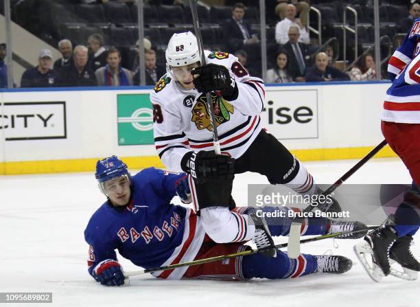 Brady Skjei of the New York Rangers trips up Patrick Kane of the Chicago Blackhawks during the first period at Madison Square Garden on January 17,...